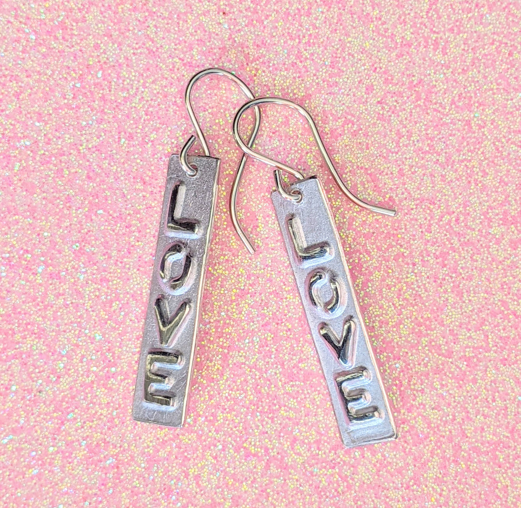 RECTANGLE "LOVE" EARRINGS | < Z-FIRE.COM > LOVE's vertical text is highlighted and polished on a rectangle frosted background with highlighted and polished edges.  .950 Fine Silver Rectangle About 2/8" Wide About 0.6 cm Wide About 1" Long About 2.5 cm Long .925 Sterling Silver Ear Wires