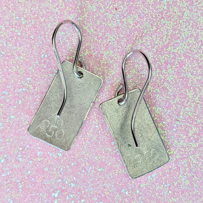 ONE HEART EARRINGS | <Z-FIRE.COM> A polished and highlighted silver heart on frosted silver rectangle background with polished edges. .950 Fine Silver Rectangles About 3/8" Wide About 9 mm Wide Approximately 5/8" Total Length About 1.6 cm Total Length .925 Sterling Silver Ear Wires