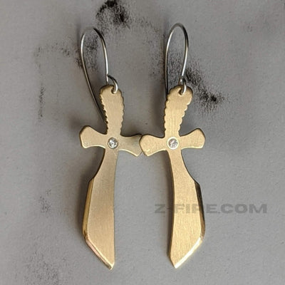 BRASS SWORD EARRINGS WITH CUBIC ZIRCONIA | < Z-FIRE.COM > A unique handcrafted blend of brass, sterling silver and cubic zirconia. Let the symbol of the sword be a reminder of the power of your words. Use them with authority to cut through any lies coming in either through your mind or directed towards you. .925 Sterling Silver Ear wires About 1.25" Total Length 2mm Cubic Zirconia Free Astrological Report Free Standard Shipping Hassle-Free Returns