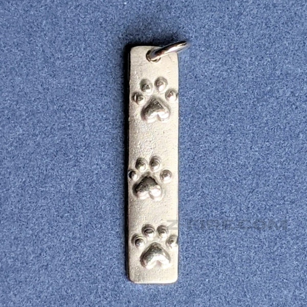 PAW - PRINTS CHARM | < Z-FIRE.COM > Cute .950 silver purity paw-print charm to keep you company when away from your pet/s. .950 Silver Paw-Print Charm 1 . 1/8" Inches in Total Length 2.75 cm Total Length 1/4" Inches Wide 6 mm Wide To add a name onto the back of the charm, use the seller's instruction box at checkout. Free Astrological Report of Choice Free standard shipping Hassle-Free Returns